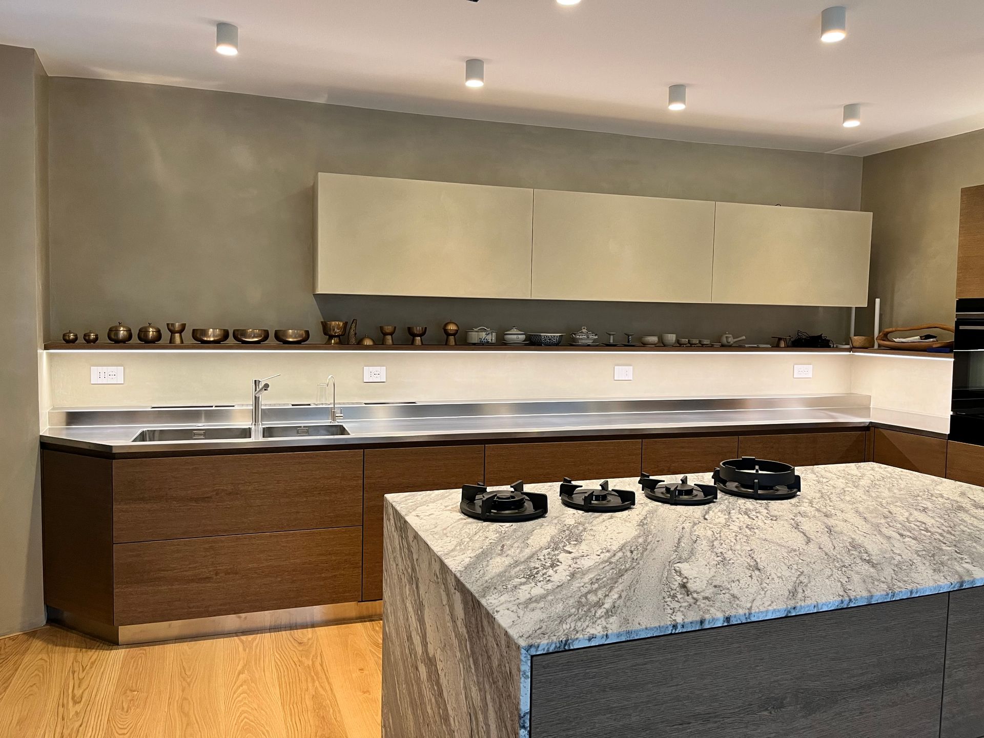 Cucina moderna con isola in pietra, mobili in legno, paraschizzi e lavello in acciaio inox.
