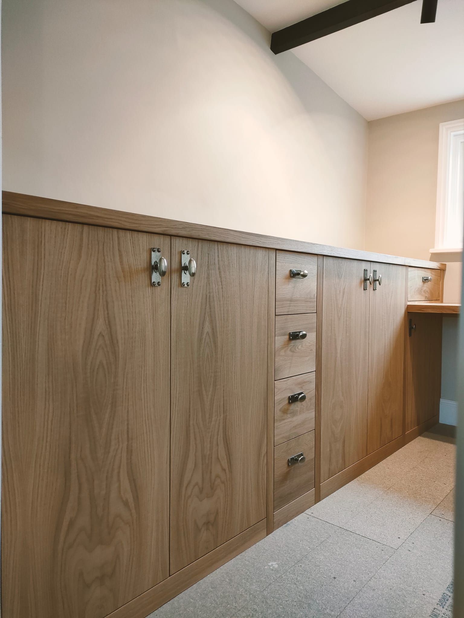 Custom light wood cabinetry with doors and drawers featuring metal hardware along a wall.