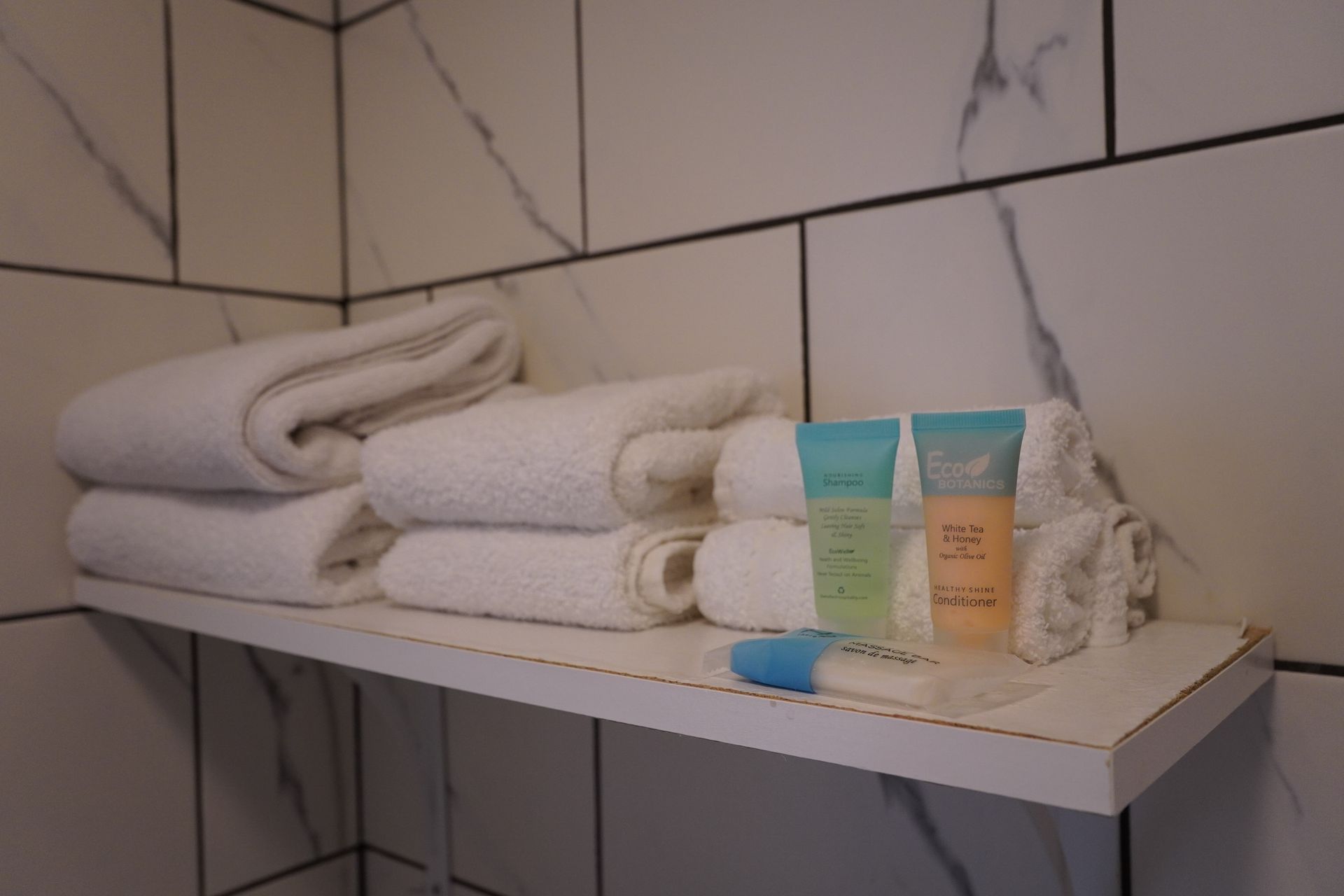 A bathroom shelf with towels and toiletries on it