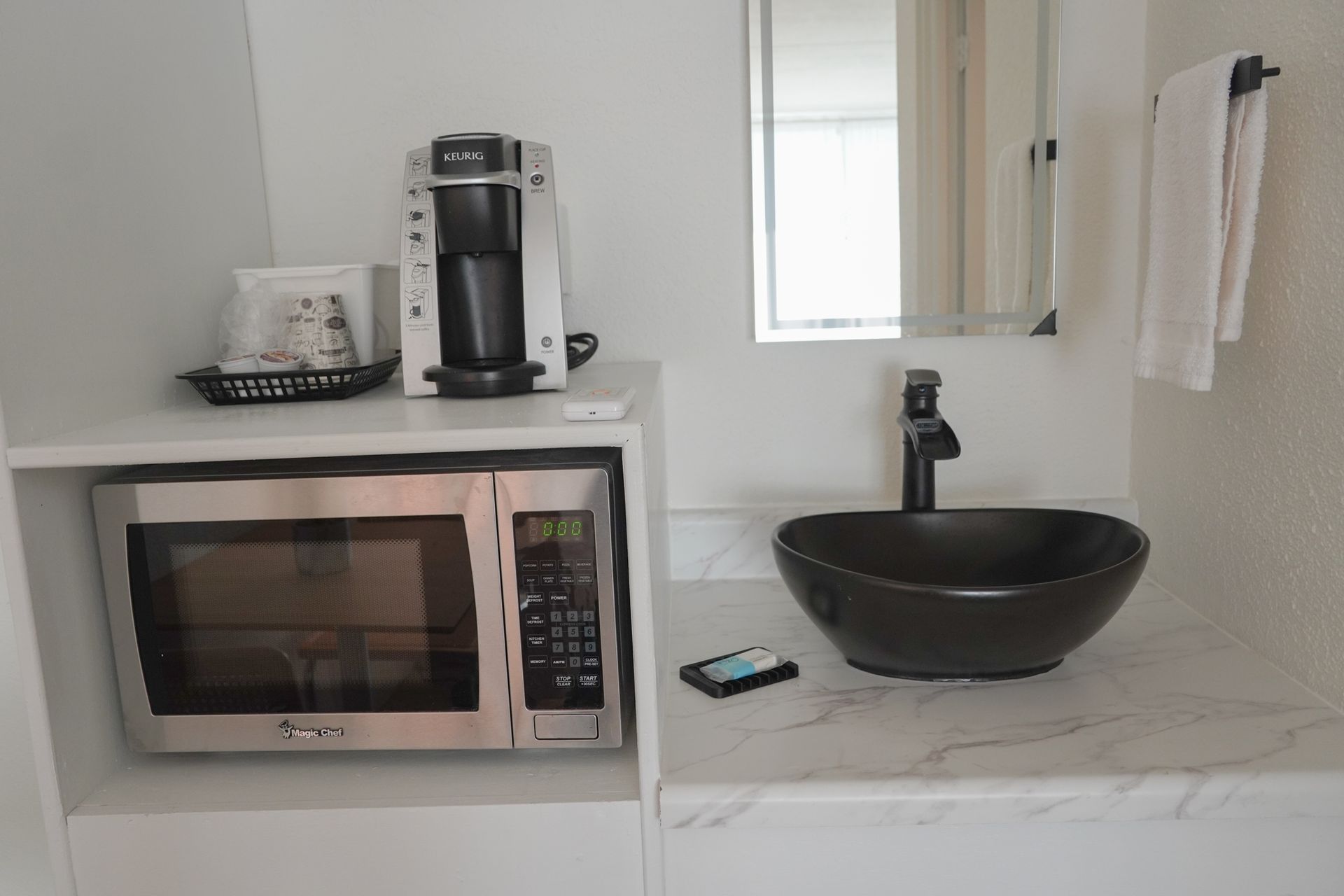 A bathroom with a sink , microwave and coffee maker