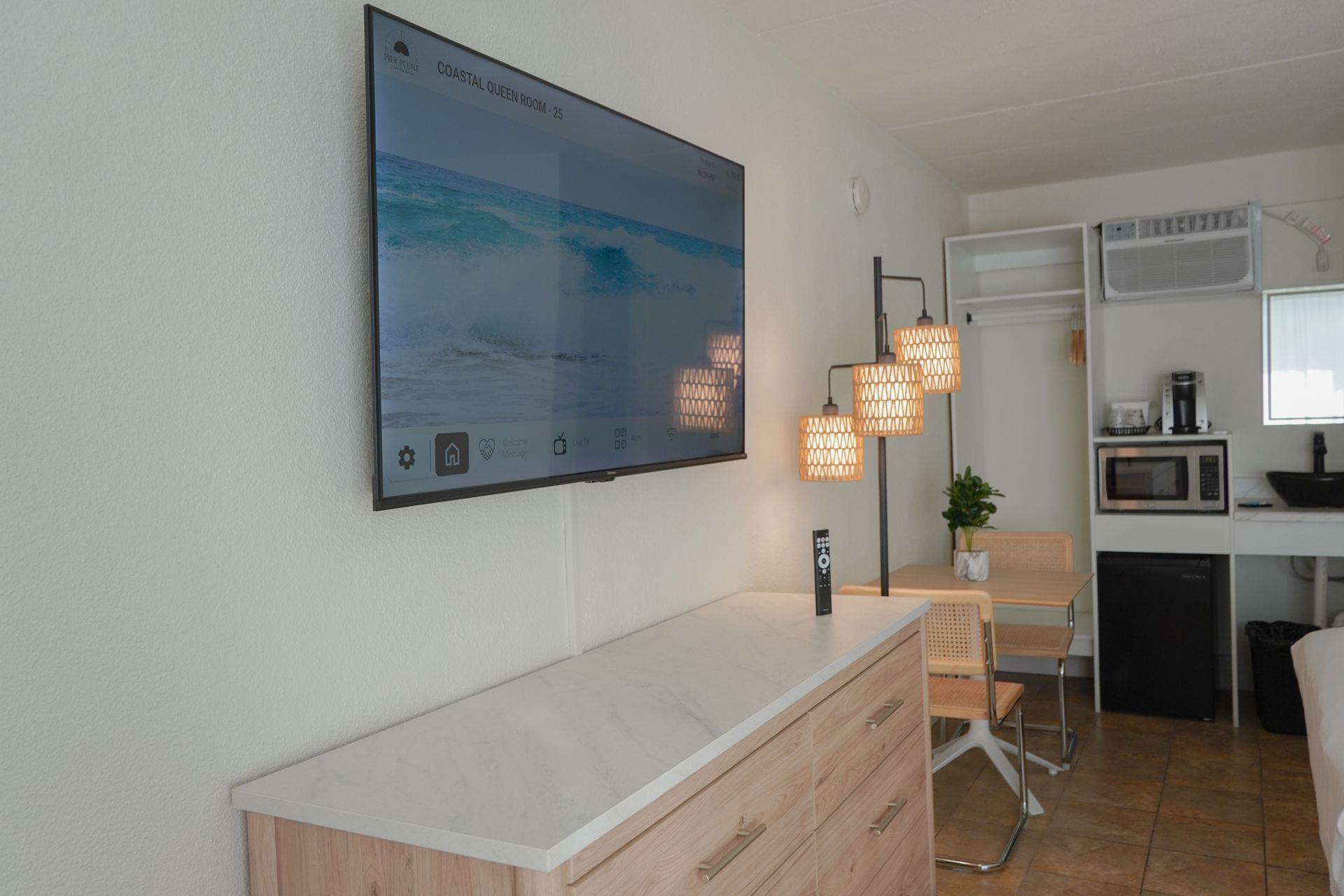 A flat screen tv is mounted on the wall above a dresser.