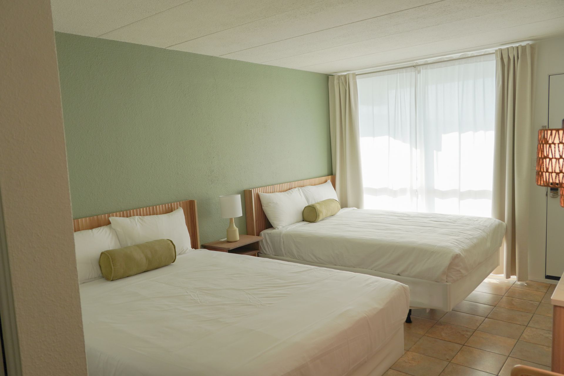 A hotel room with two beds and a large window