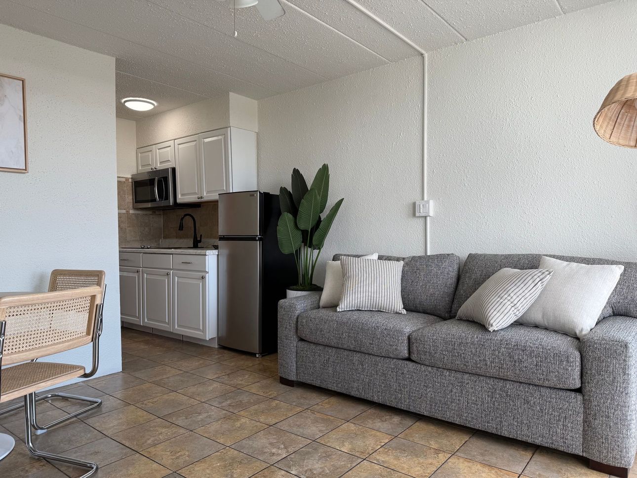 A living room with a couch , chair , table and kitchen.
