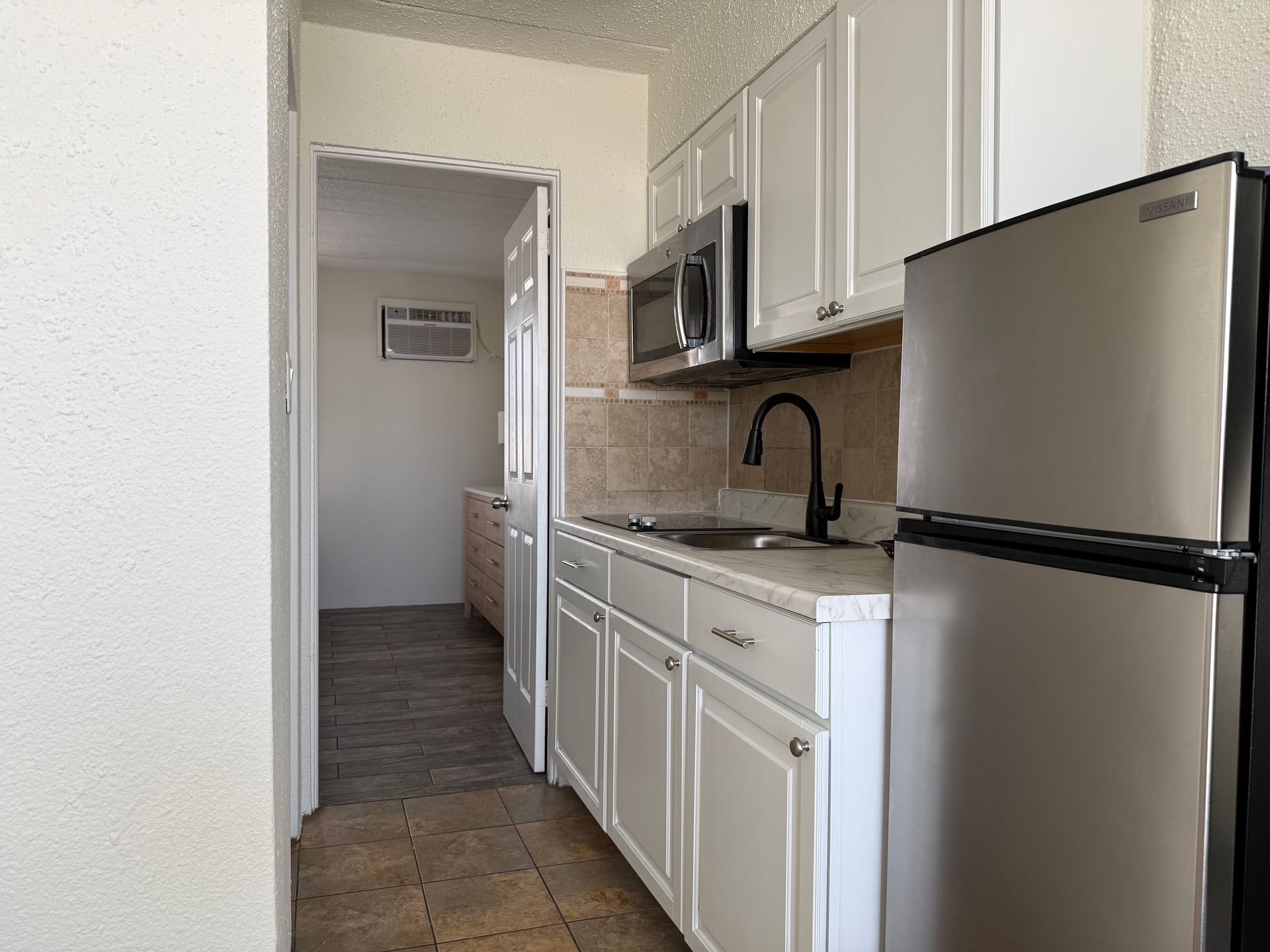 A kitchen with white cabinets and a stainless steel refrigerator