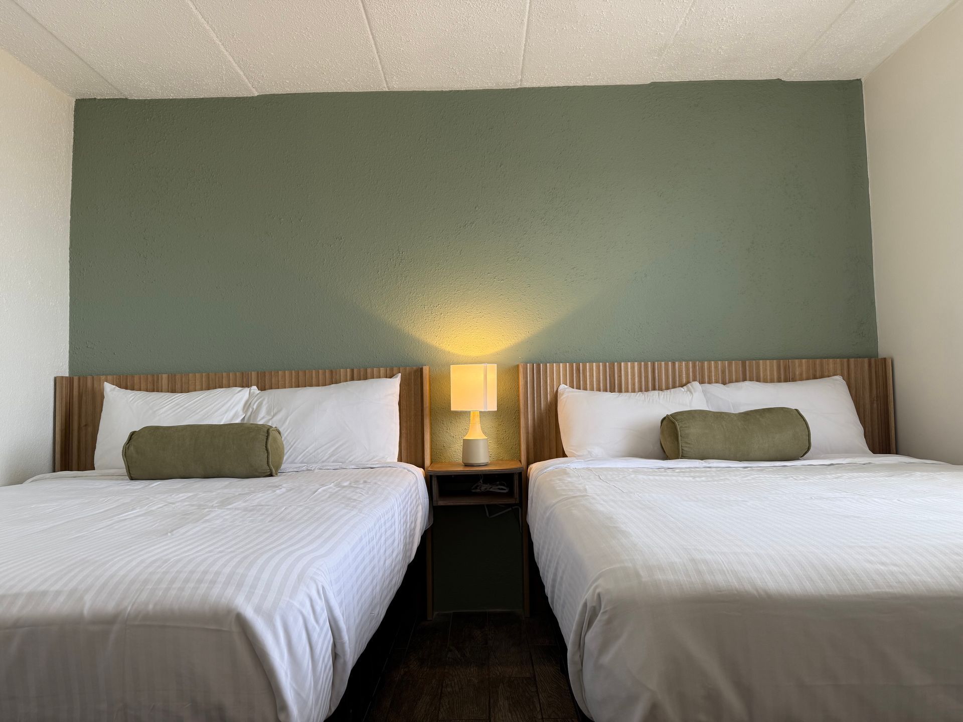 A hotel room with two beds and a lamp