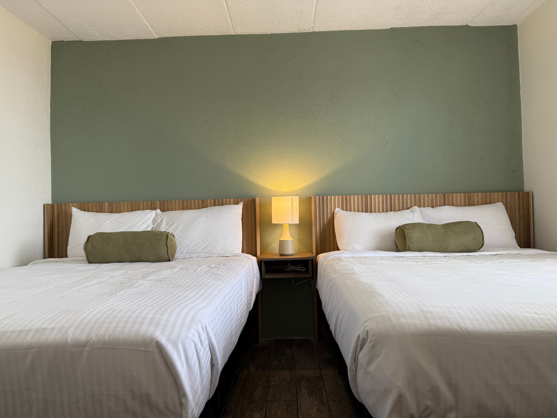 A hotel room with two beds and a lamp.