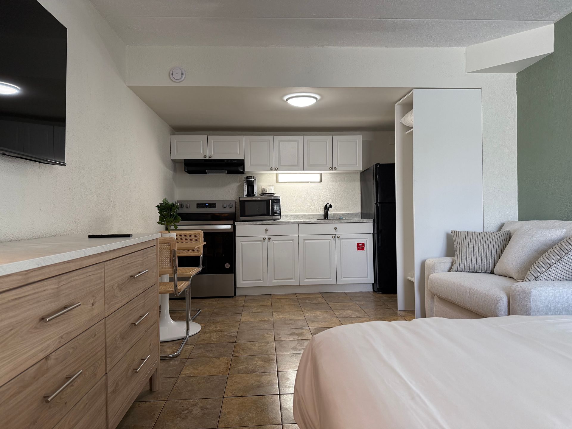A bedroom with a bed , couch , television and kitchen