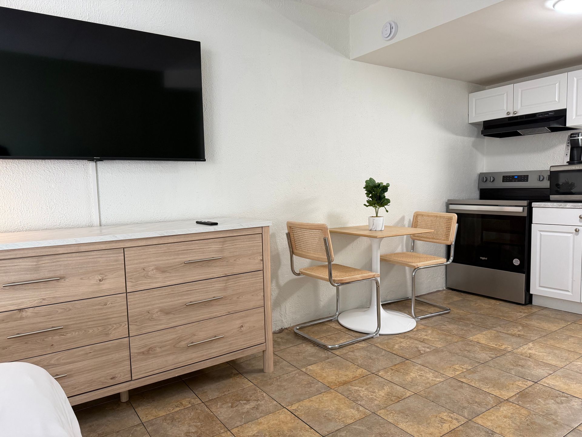 A kitchen with a table and chairs and a flat screen tv