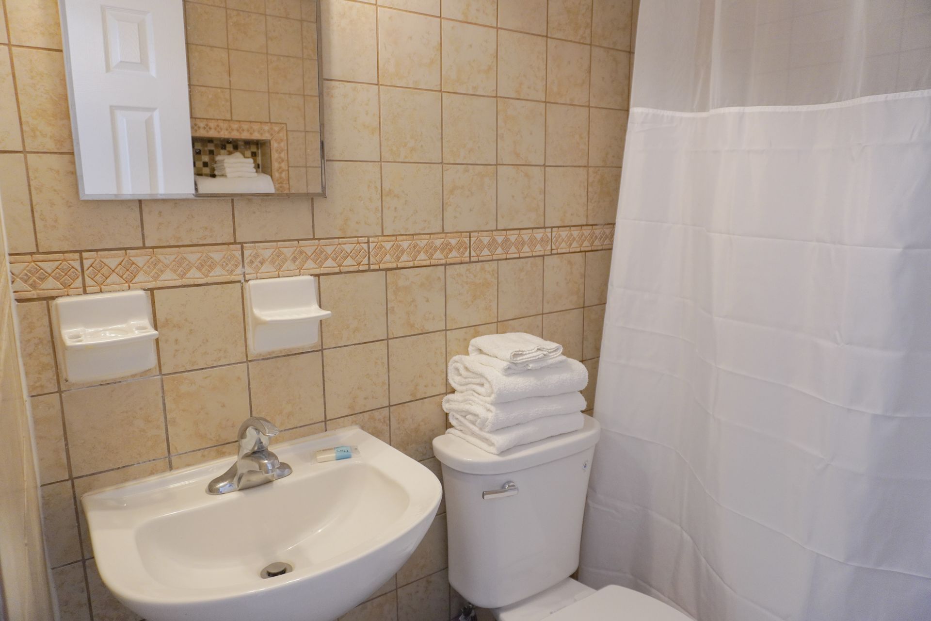 A bathroom with a sink , toilet and shower curtain.