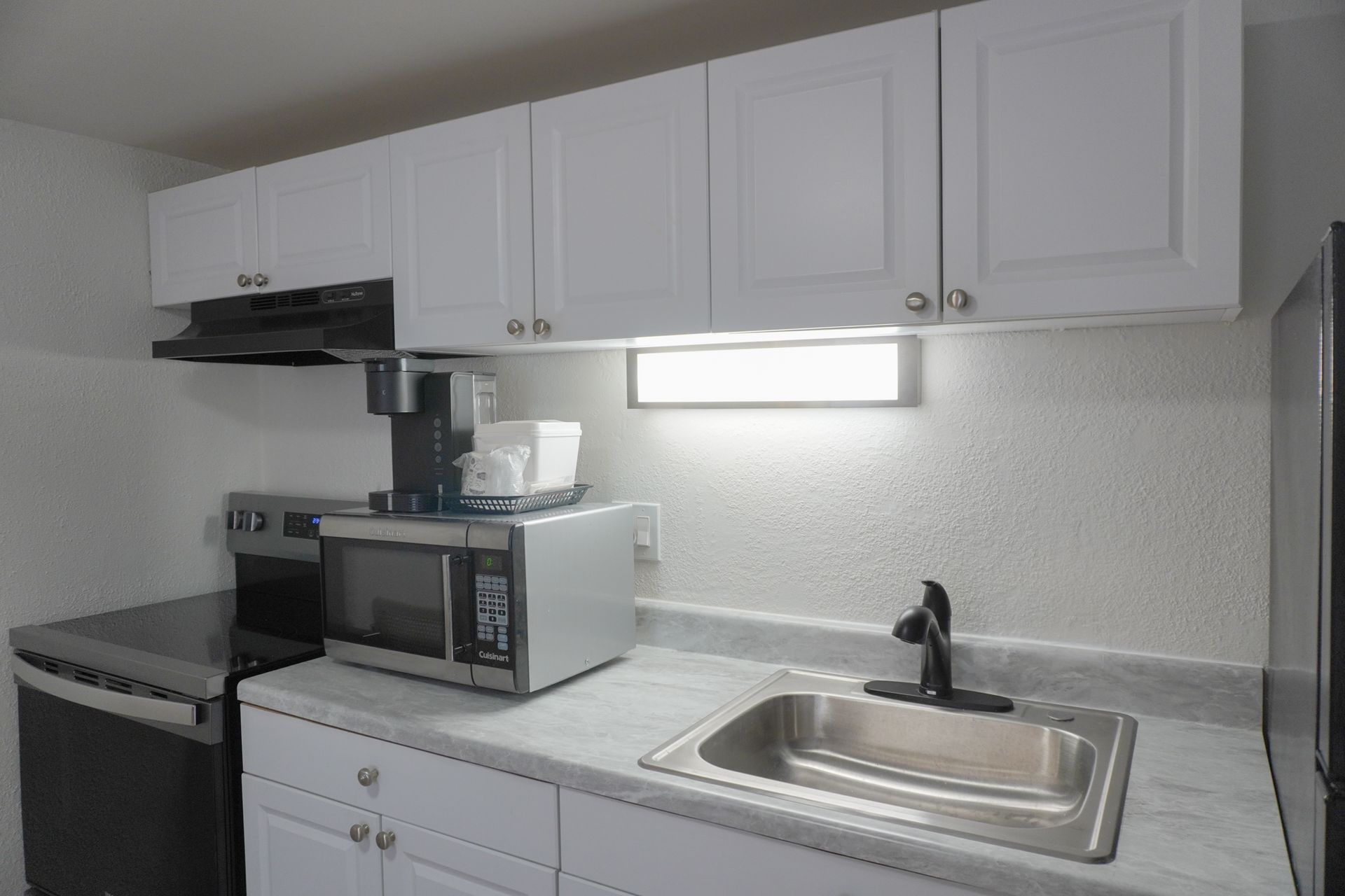 A kitchen with a sink , stove , microwave and dishwasher