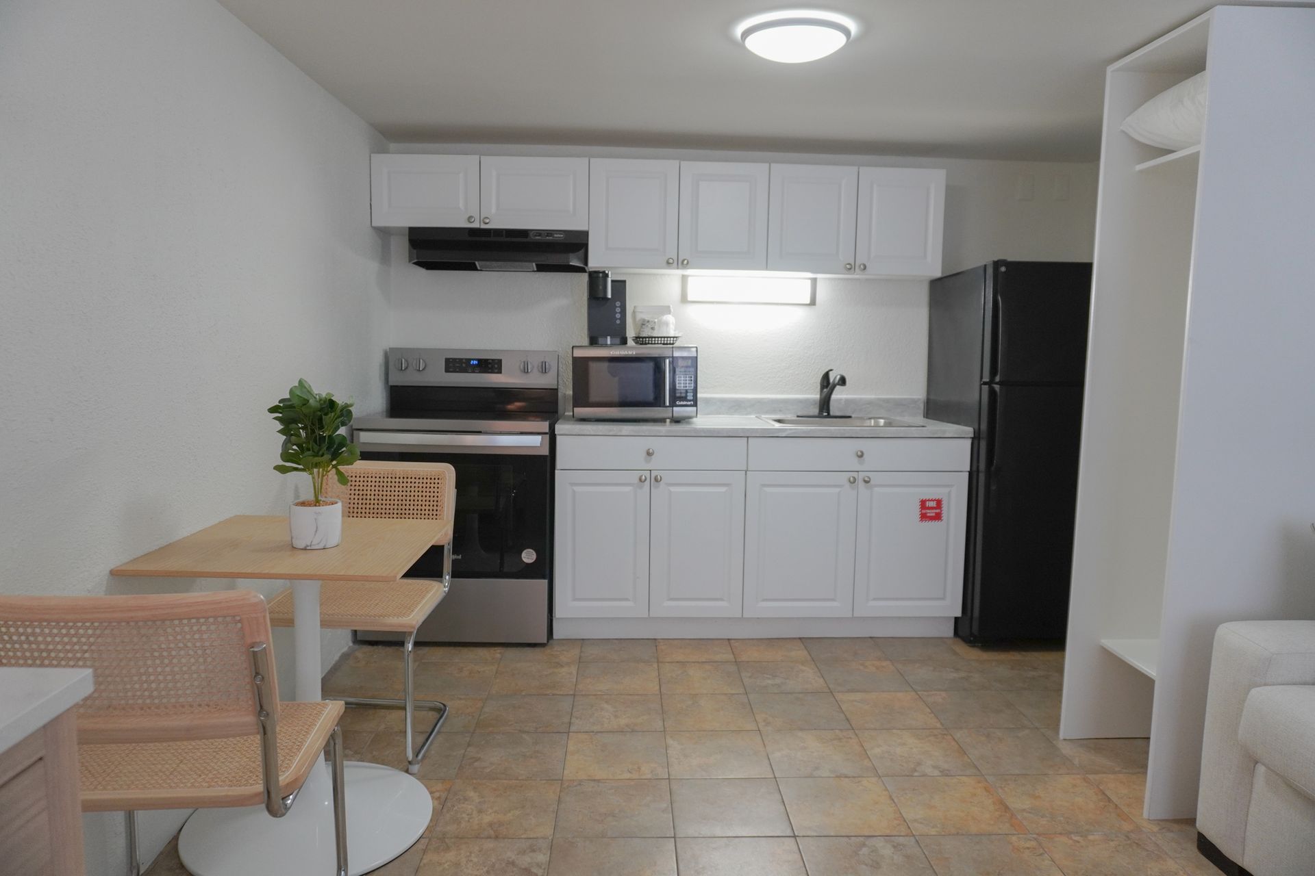 A kitchen with white cabinets and a black refrigerator