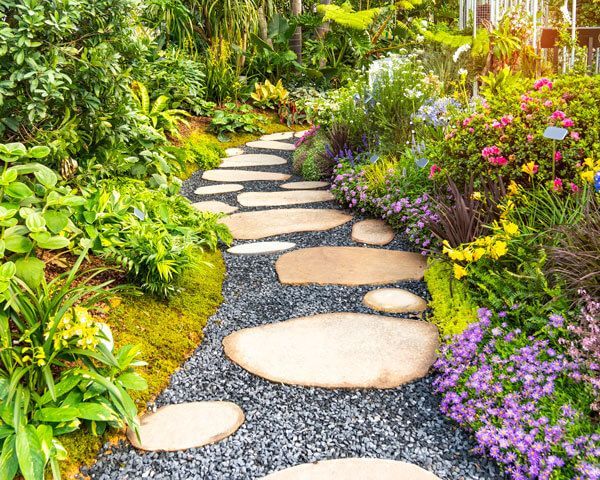 Curving garden path with stepping stones through lush greenery and colorful flowers