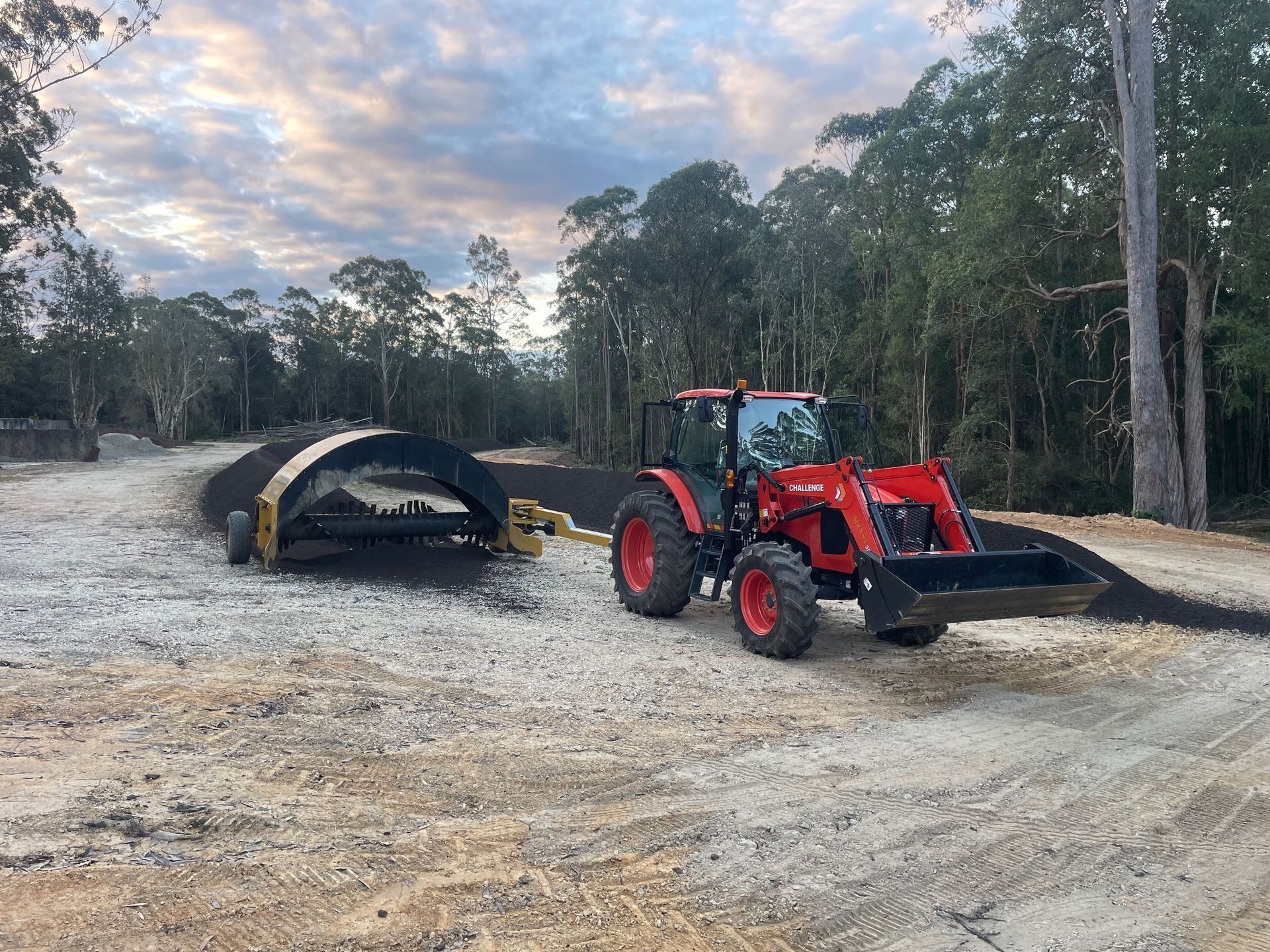 Red Tractor Pulling a Conveyor Belt, Spreading Dark Materia — Blue Dog Earthmoving Landscape Supplies in Newee Creek, NSW