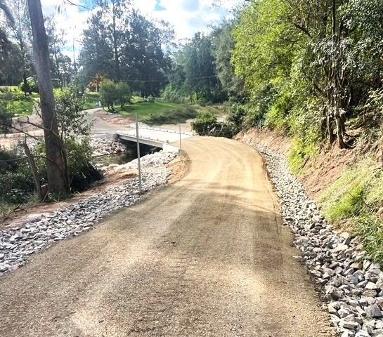 Gravel Road Curving Into a Wooded Area, Bridge in the Background — Blue Dog Earthmoving Landscape Supplies in Newee Creek, NSW