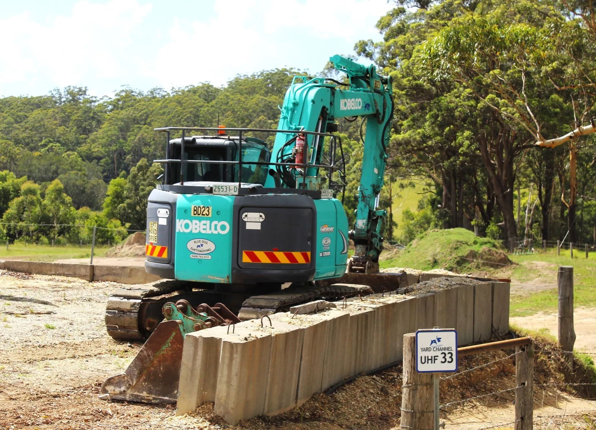 Green Kobelco Excavator on a Concrete Structure at a Worksite — Blue Dog Earthmoving Landscape Supplies in Newee Creek, NSW