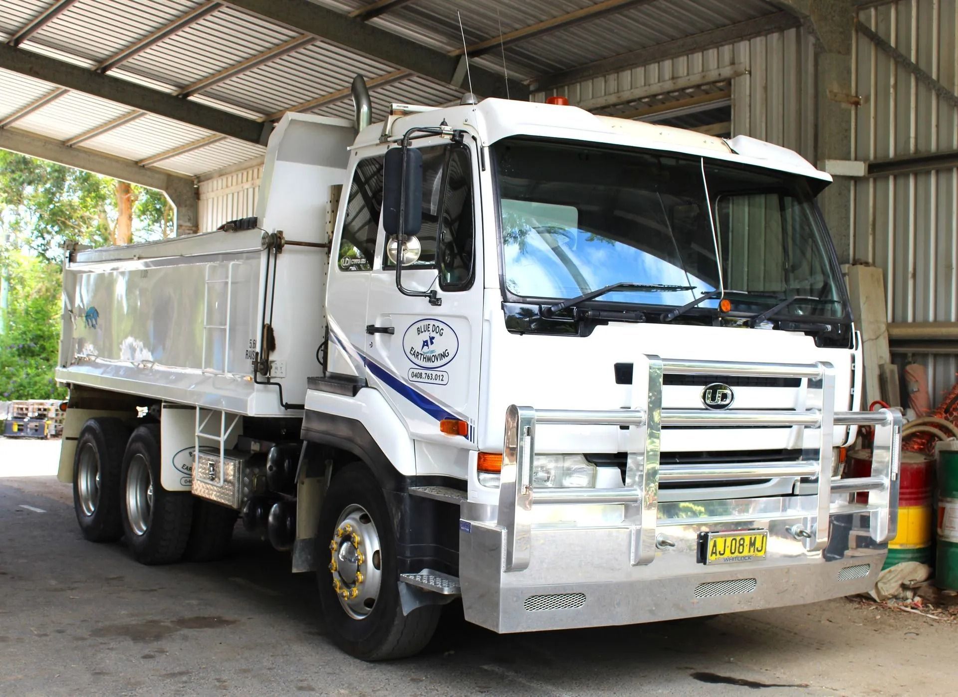 White Dump Truck Parked Under a Corrugated Metal Roof — Blue Dog Earthmoving Landscape Supplies in Newee Creek, NSW