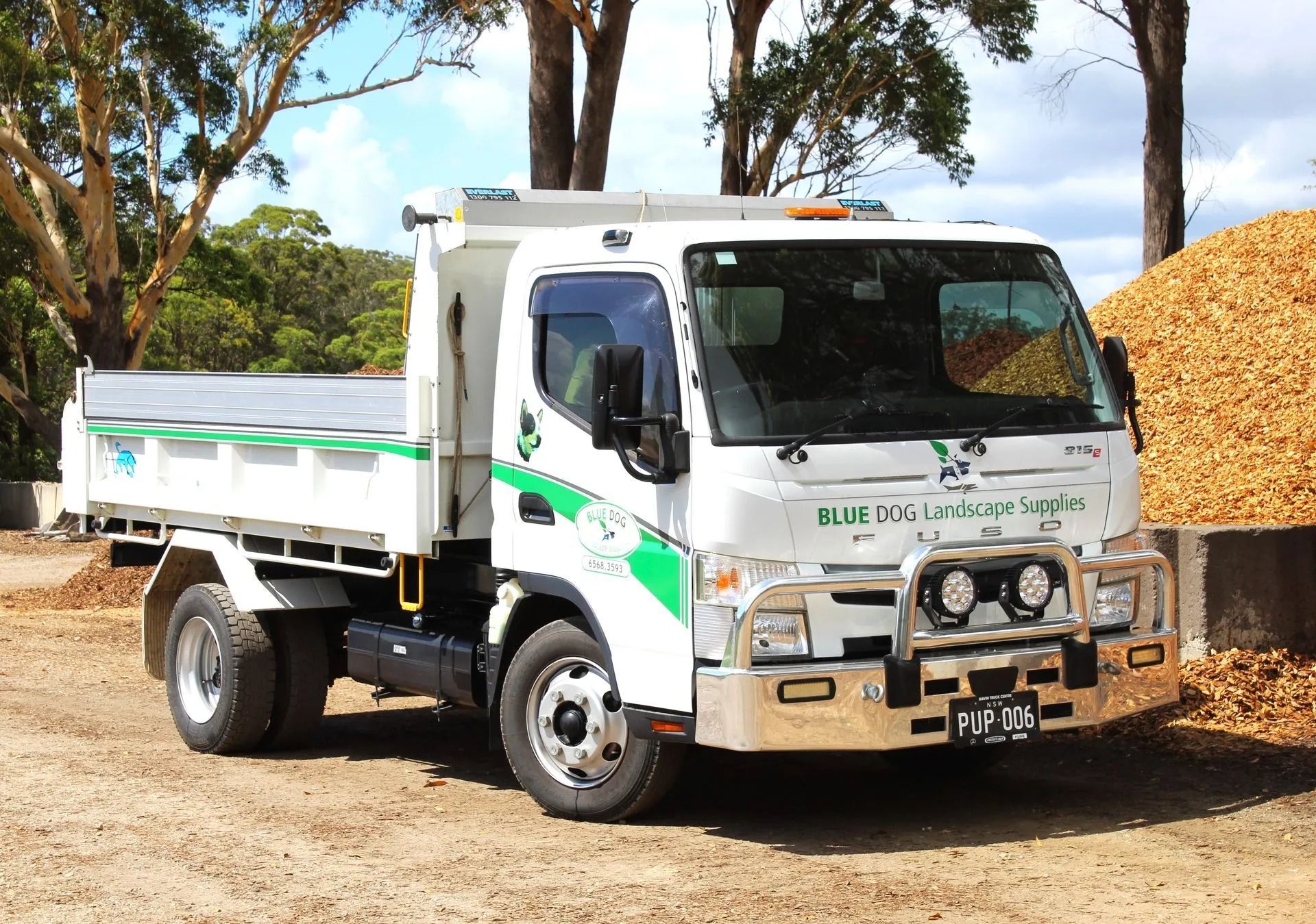 White Dump Truck, With Green Accents, Parked Near a Pile of Wood Chips — Blue Dog Earthmoving Landscape Supplies in Newee Creek, NSW