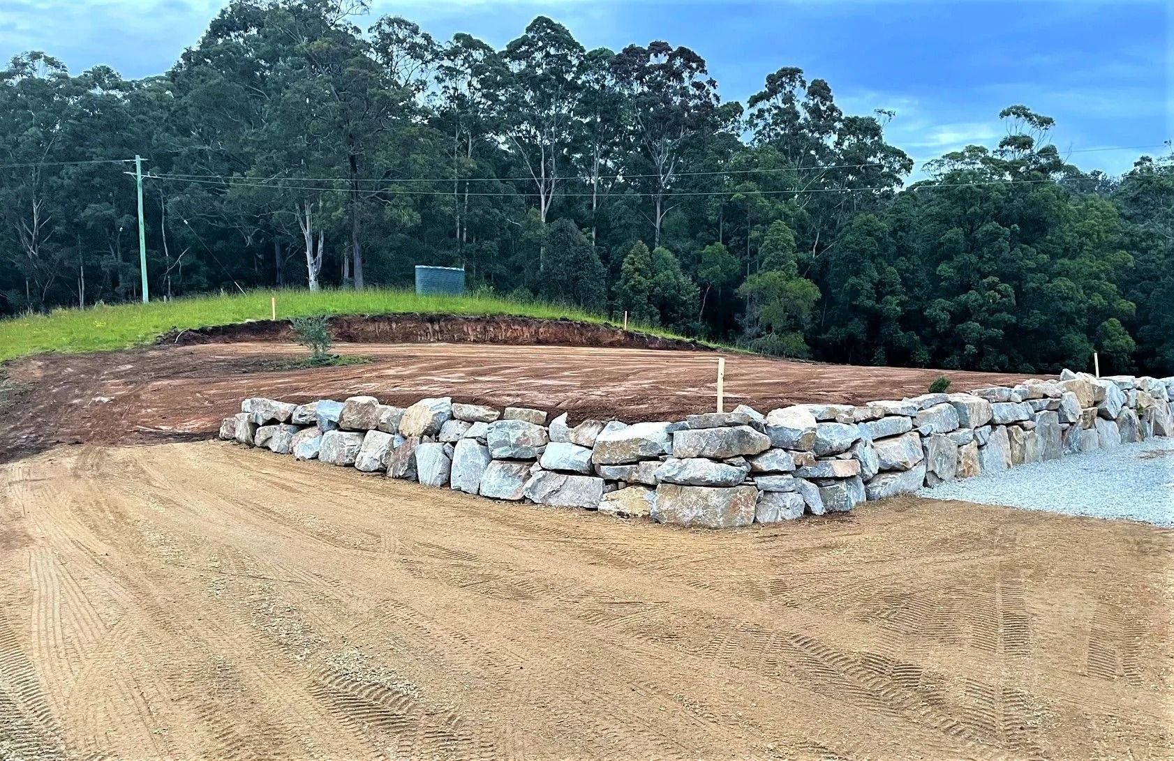 Stone Retaining Wall Bordering a Dirt Lot — Blue Dog Earthmoving Landscape Supplies in Newee Creek, NSW