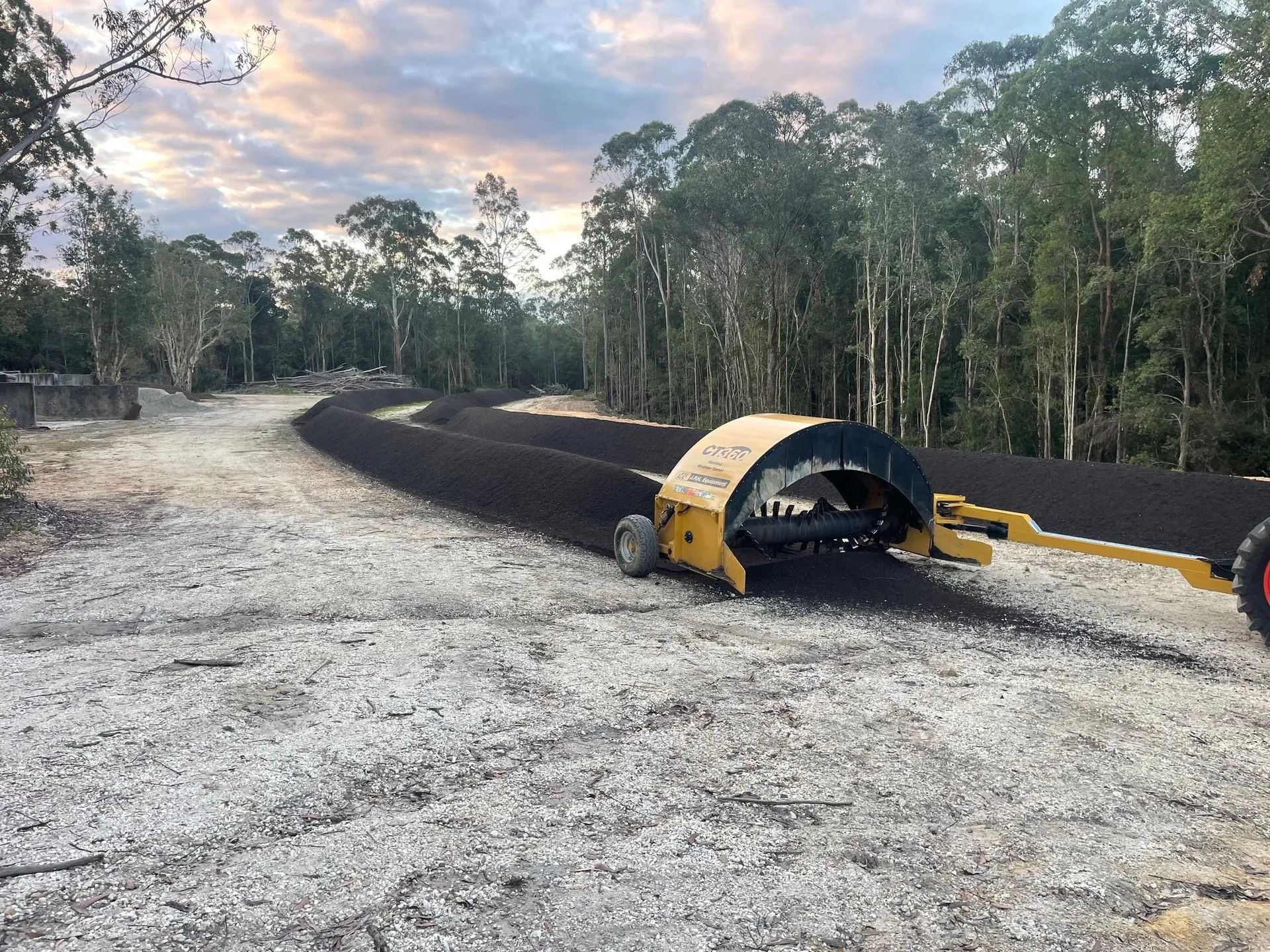 a Yellow Machine Laying Down Black Asphalt on a Gravel Road — Blue Dog Earthmoving Landscape Supplies in Scotts Head, NSW
