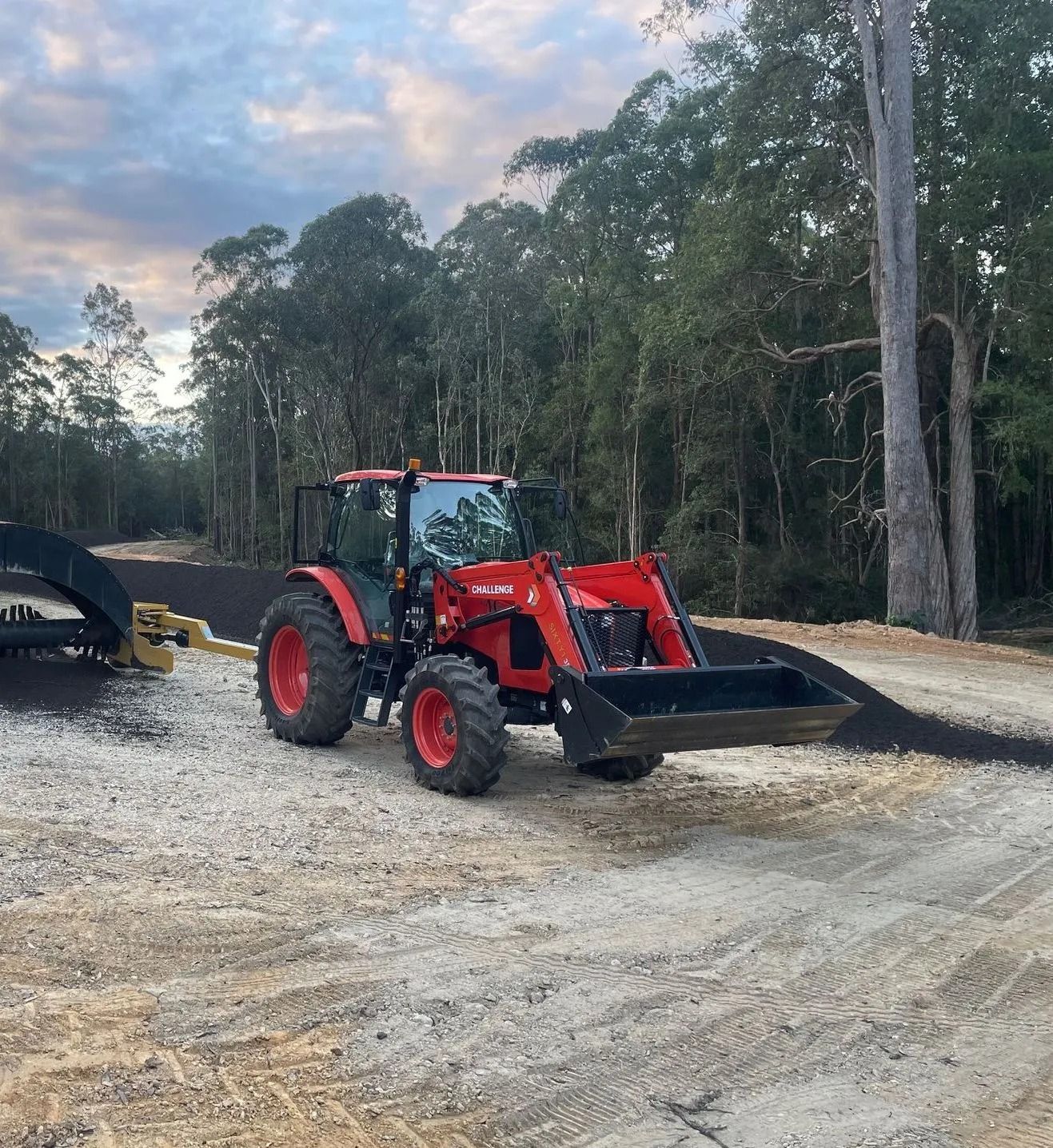 Red Tractor With Front Loader on a Gravel Road — Blue Dog Earthmoving Landscape Supplies in Newee Creek, NSW