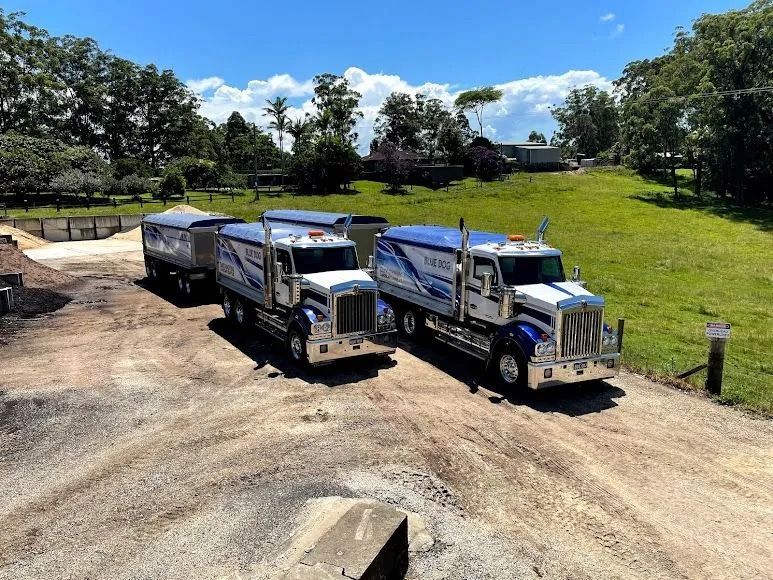 Two White and Blue Semi-trucks Parked on a Gravel Road — Blue Dog Earthmoving Landscape Supplies in Newee Creek, NSW