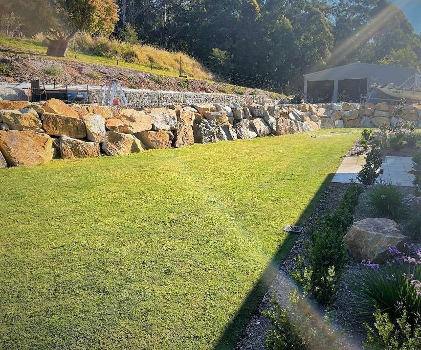 Green Lawn in Front of a Large Stone Retaining Wall — Blue Dog Earthmoving Landscape Supplies in Newee Creek, NSW