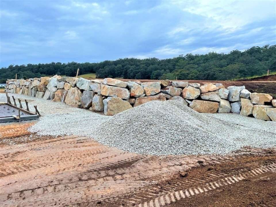 A Pile of Gravel and Large Stones Next to a Rock Wall — Blue Dog Earthmoving Landscape Supplies in Newee Creek, NSW
