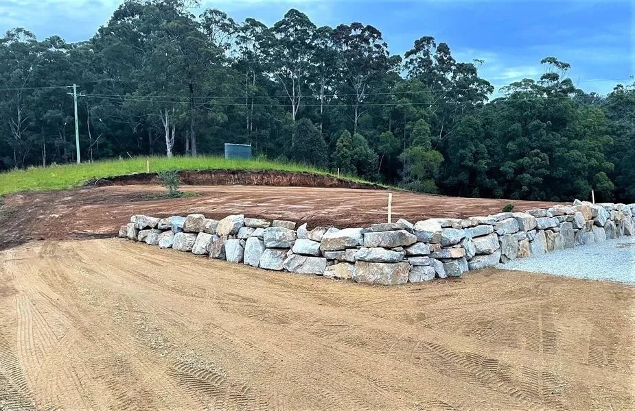 Stone Retaining Wall on a Hillside With a Gravel Driveway — Blue Dog Earthmoving Landscape Supplies in Newee Creek, NSW