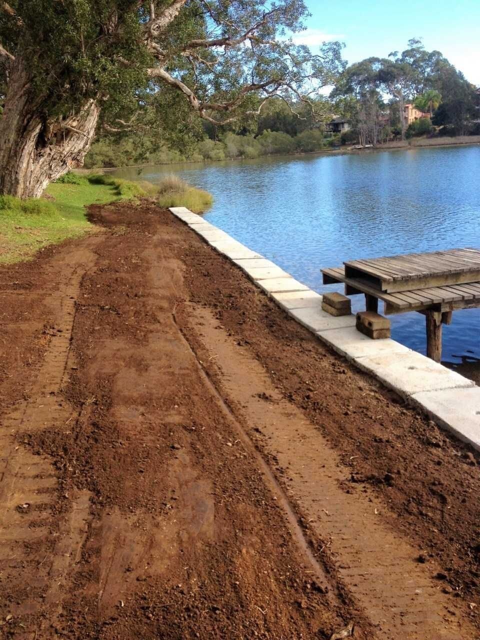 Dirt Path Next to a Waterway, Concrete Wall, and a Wooden Pier — Blue Dog Earthmoving Landscape Supplies in Newee Creek, NSW