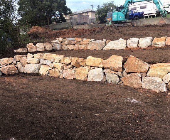 Stone Retaining Walls on a Hillside With Freshly Turned Soil — Blue Dog Earthmoving Landscape Supplies in Newee Creek, NSW