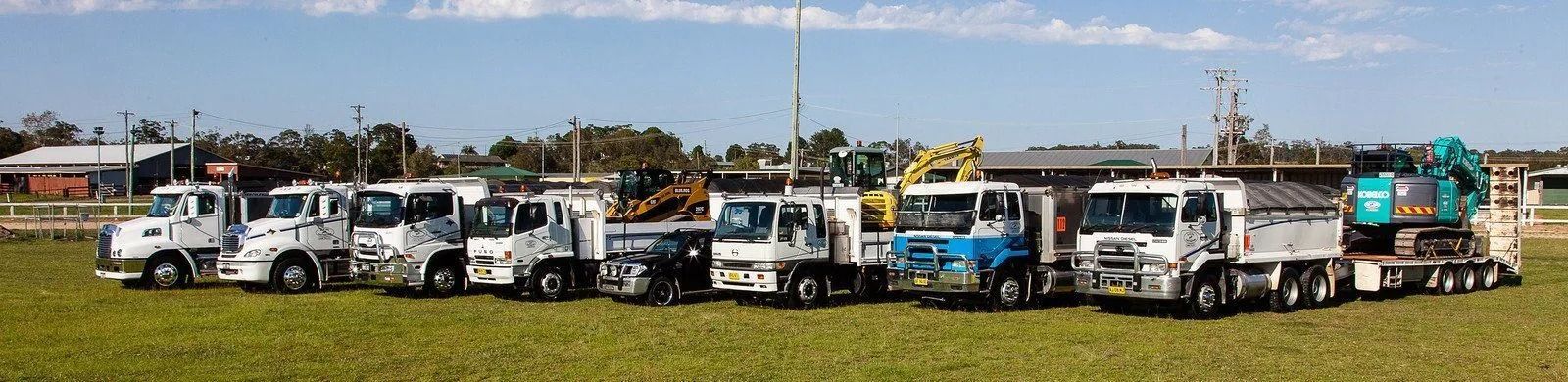 Several Trucks Parked on a Grassy Area — Blue Dog Earthmoving Landscape Supplies in Newee Creek, NSW