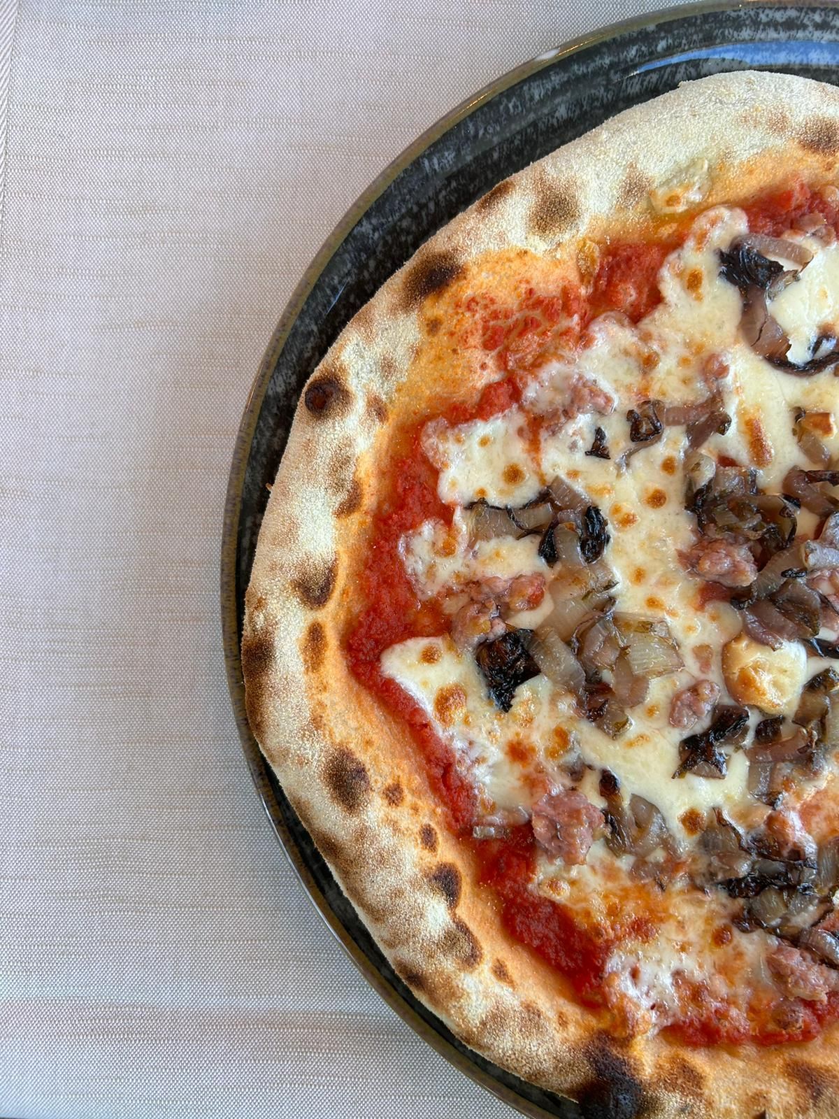 Una pizza con pomodori e formaggio è su un piatto su un tavolo.