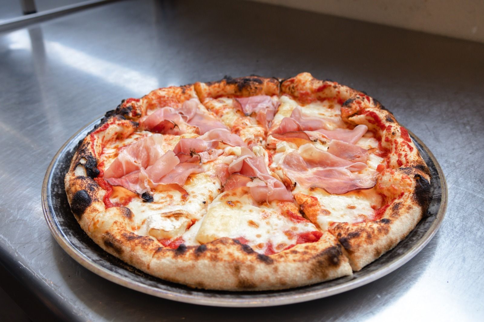 Una pizza è appoggiata su un piatto su un tavolo di legno.