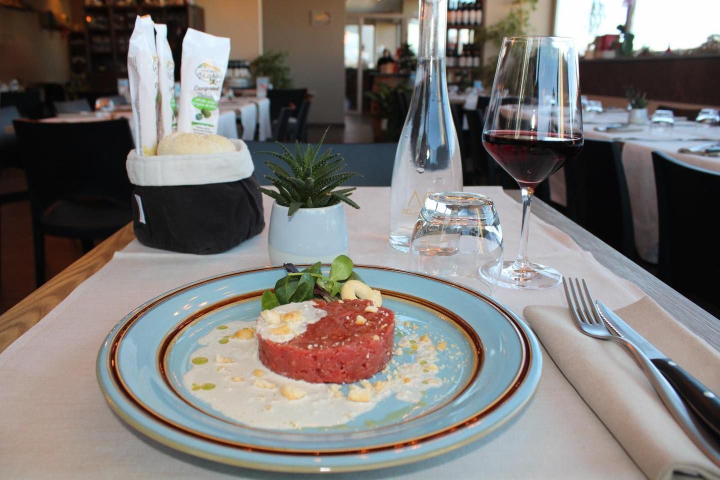 Un piatto di cibo è sul tavolo accanto a un bicchiere di vino.