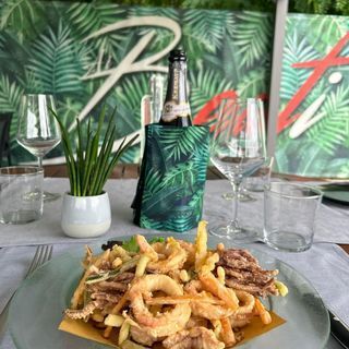 Un piatto di cibo e una bottiglia di vino su un tavolo.