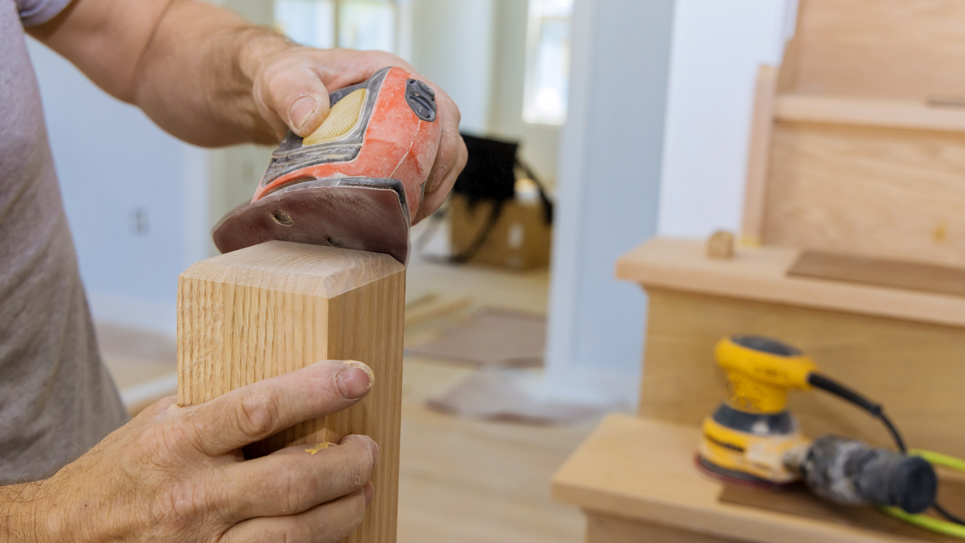 A man is sanding a piece of wood with a sander.