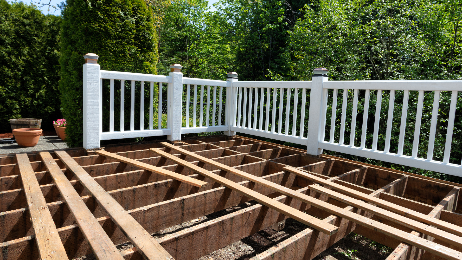 A wooden deck with a white railing is being built.