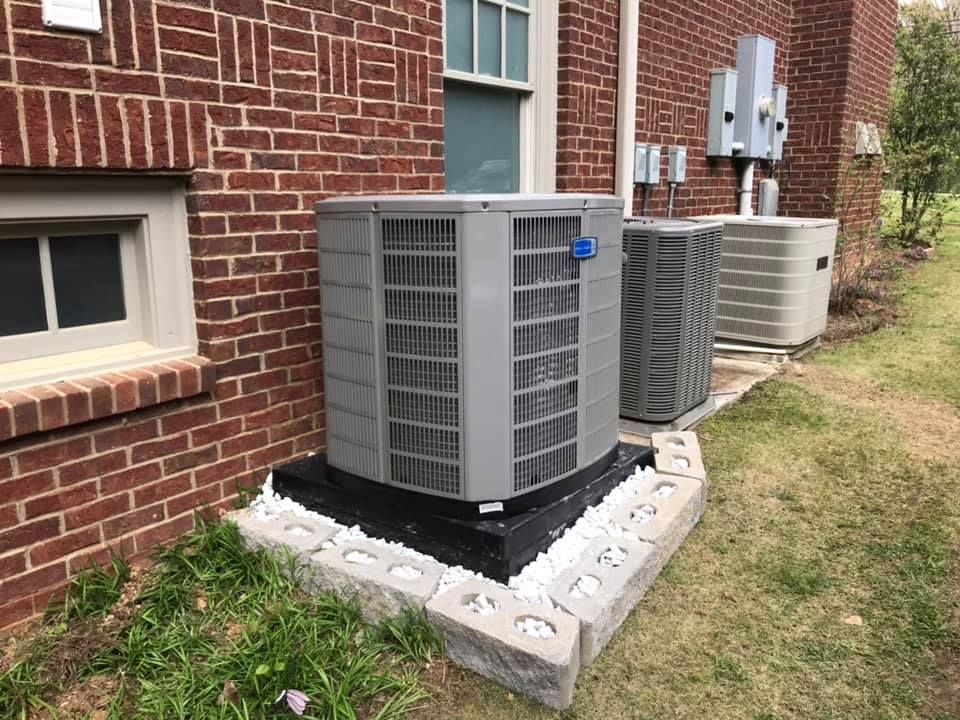Two air conditioners are sitting on the side of a brick building.