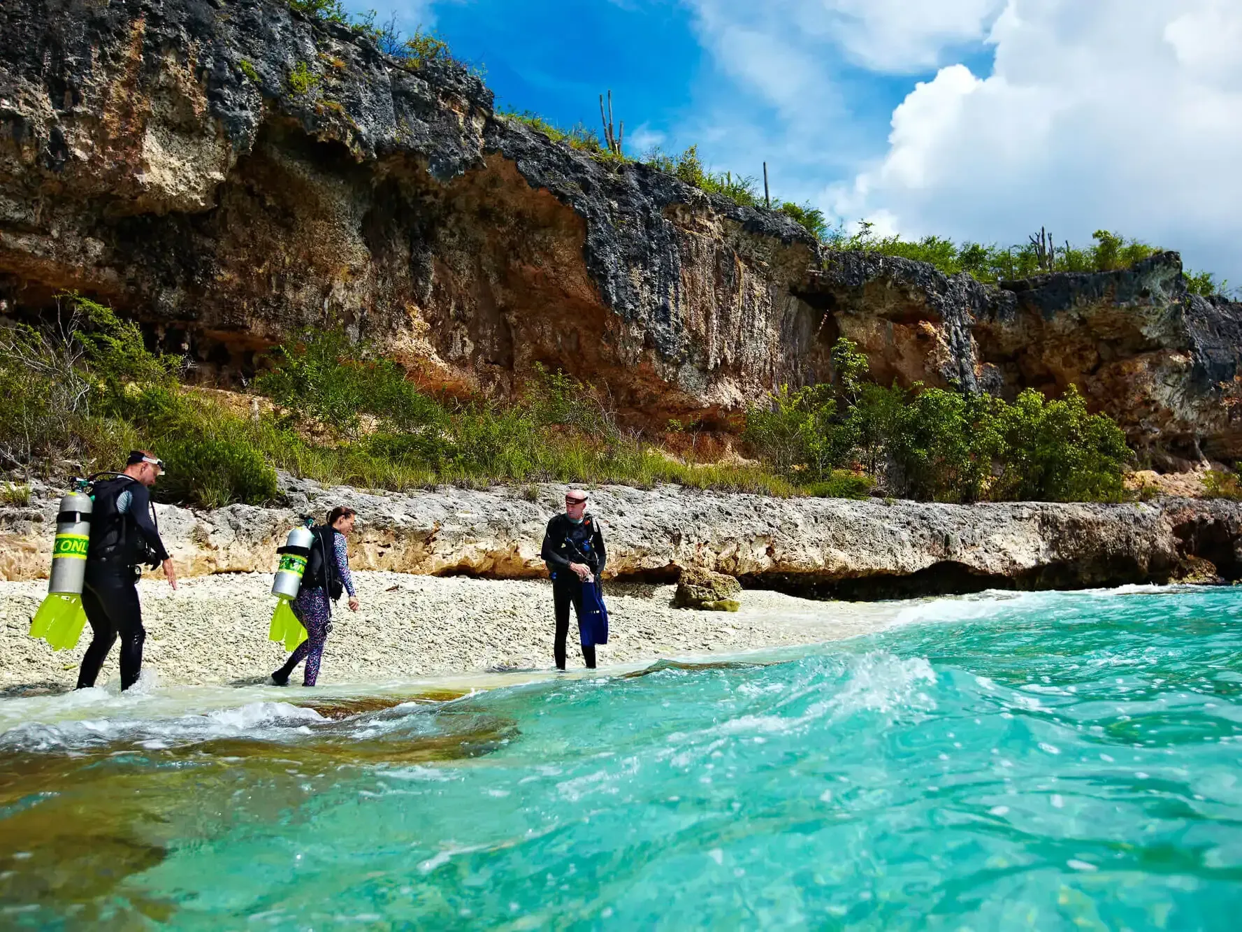 A group of scuba divers are walking out of the ocean of Bonaire.
