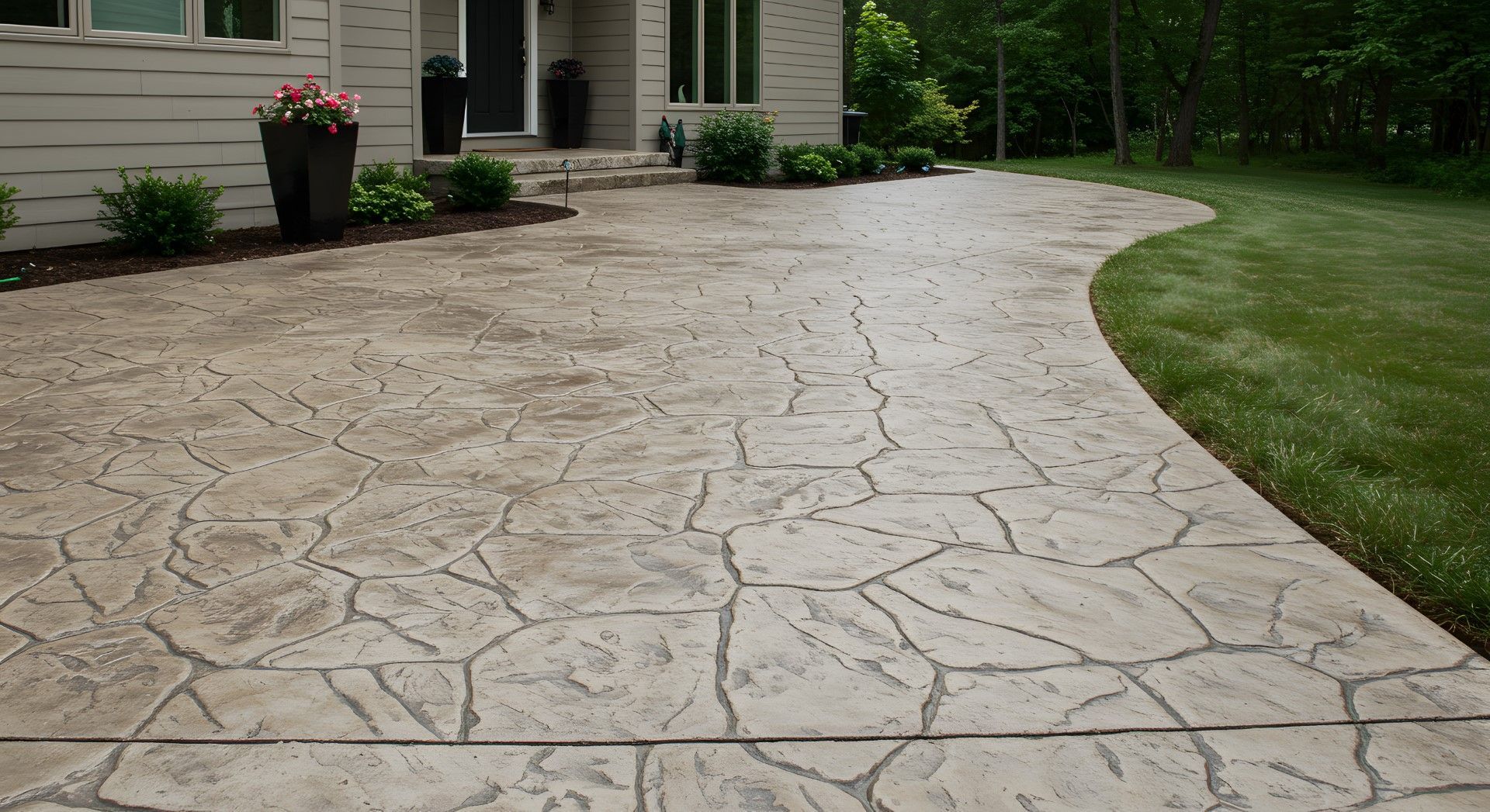 Stamped concrete patio with a stone pattern leading from a house towards green grass.