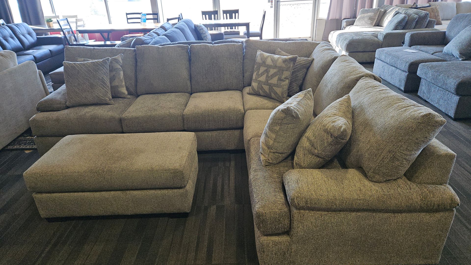 Gray sectional sofa with ottoman in a furniture store.