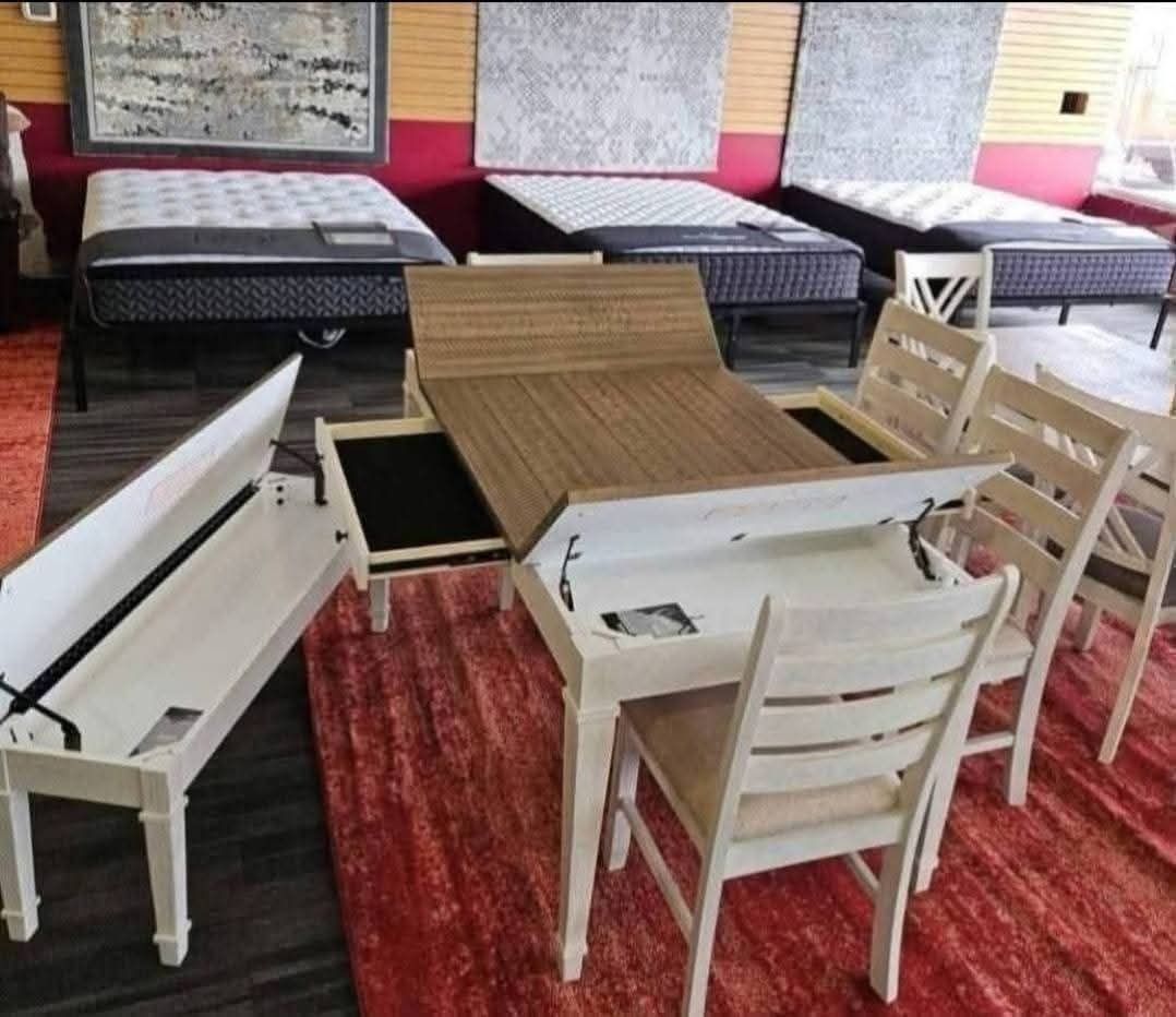 Furniture showroom featuring a white dining table with chairs, a bench, and mattresses.