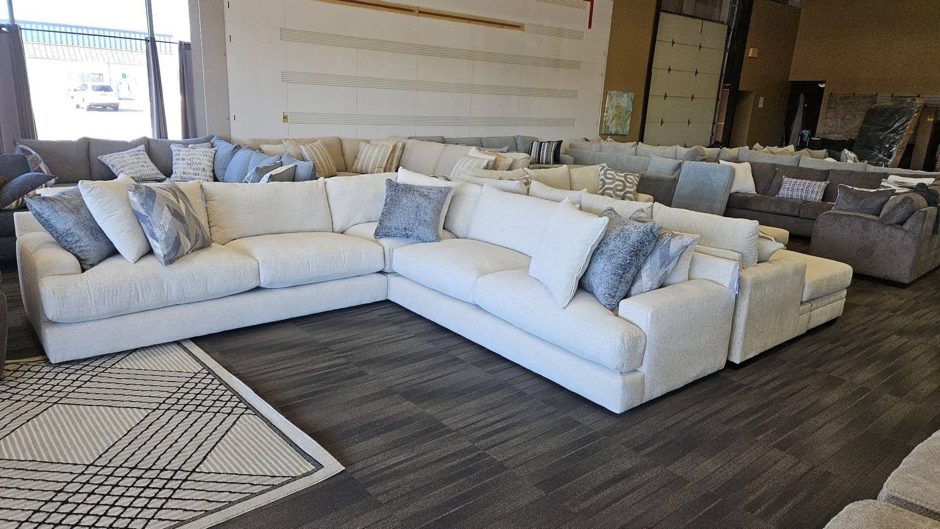 White sectional sofa with blue pillows in a showroom.