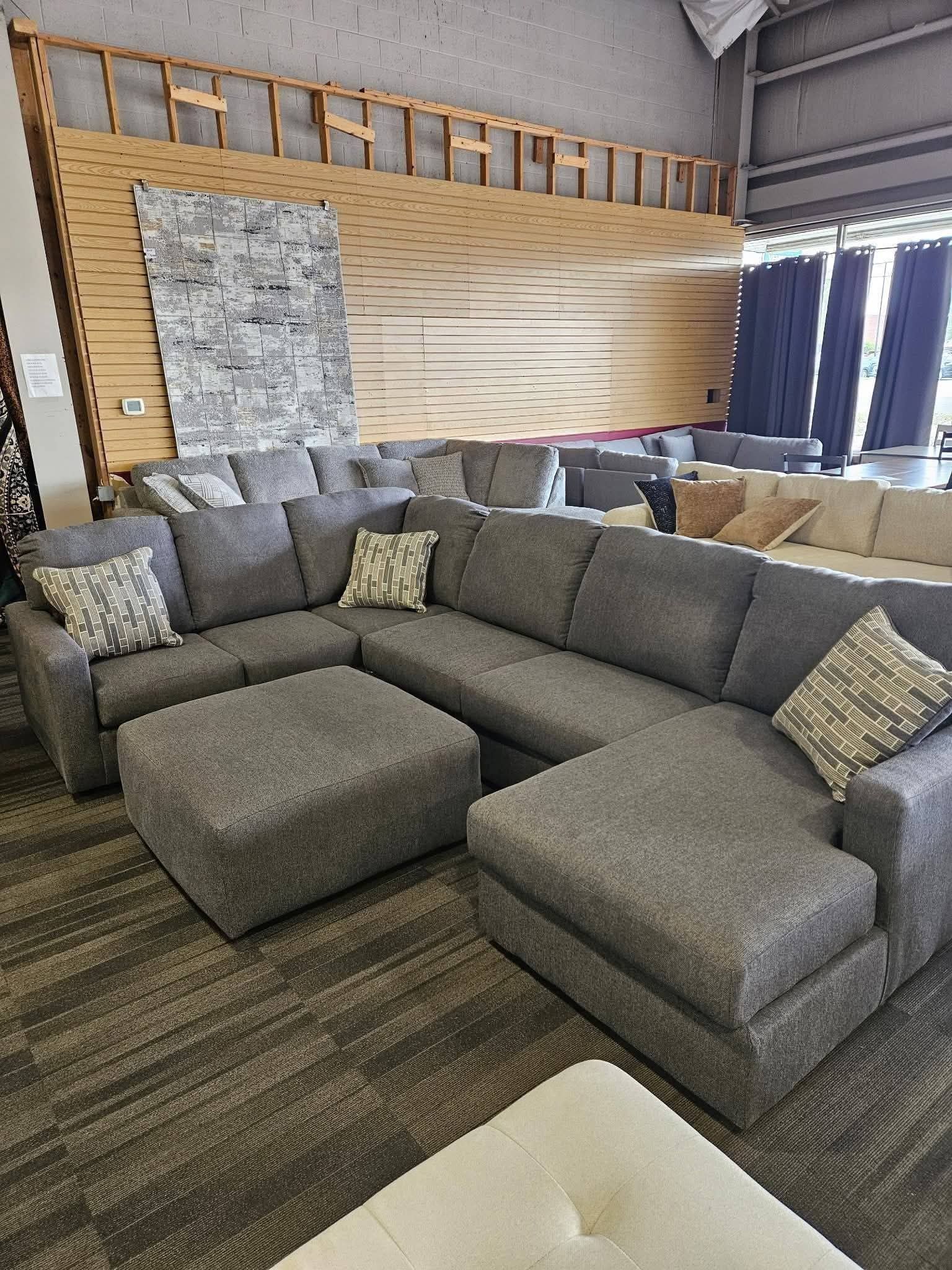 Gray sectional sofa with ottoman in a showroom.