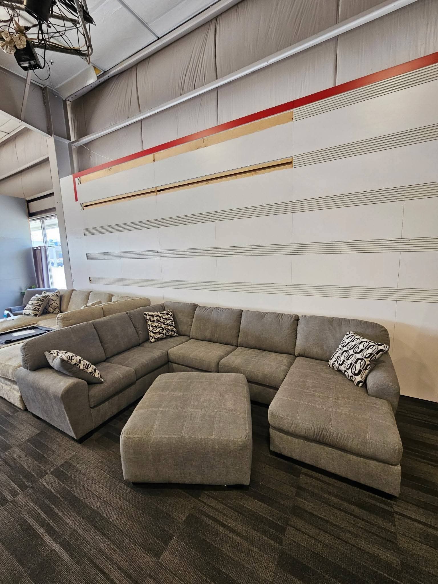 Gray sectional sofa and ottoman in a showroom.