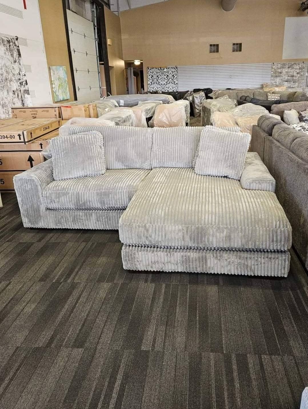 Gray corduroy sectional sofa in a warehouse.