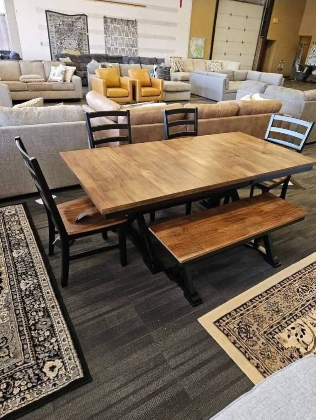 Dining table set with bench and two chairs, inside a furniture store.