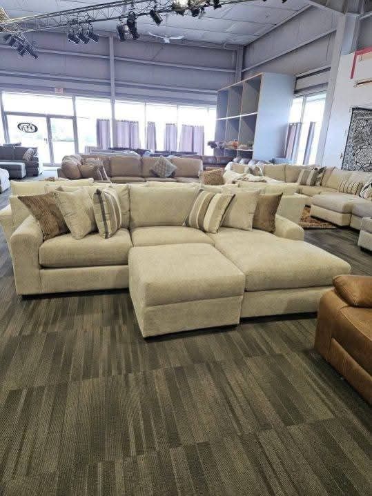Beige sectional sofa with ottoman in a furniture store showroom.