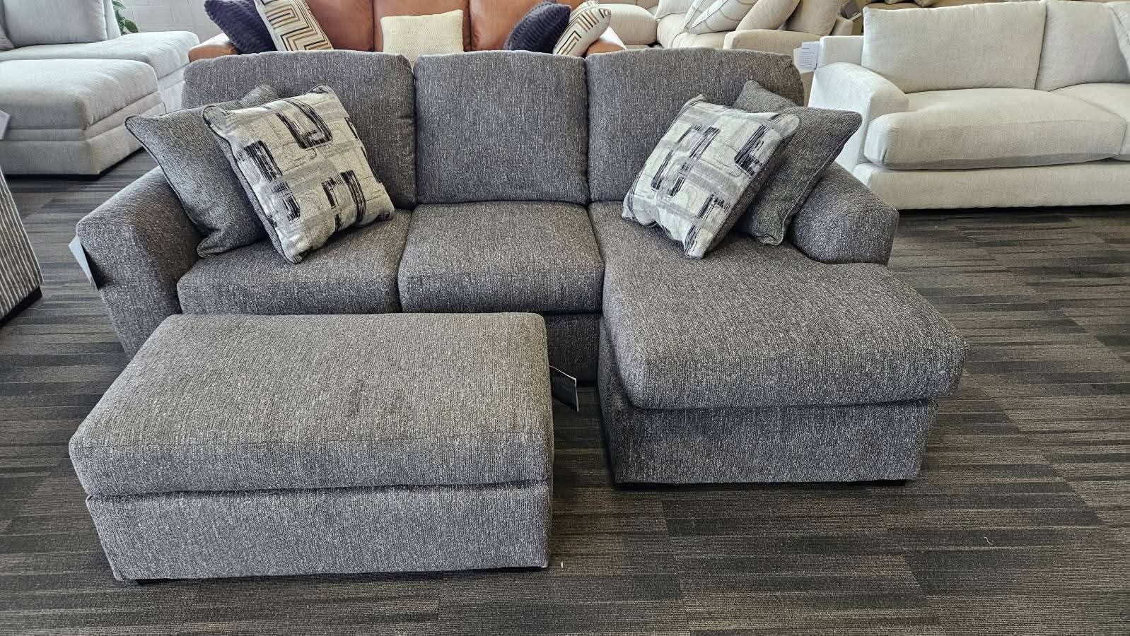 Gray sectional sofa with matching ottoman and patterned pillows.