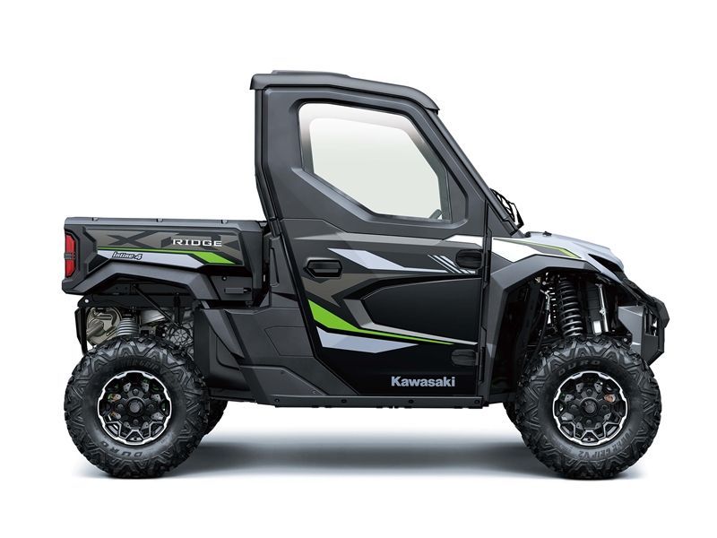Black and green Kawasaki side-by-side with enclosed cab, black wheels, and a small cargo bed.